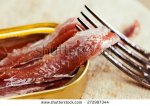 stock-photo-closeup-of-anchovies-in-an-opened-tin-can-on-wood-with-a-fork-272997344